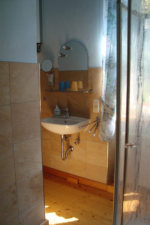 Badezimmer mit Waschbecken, Spiegel und Dusche