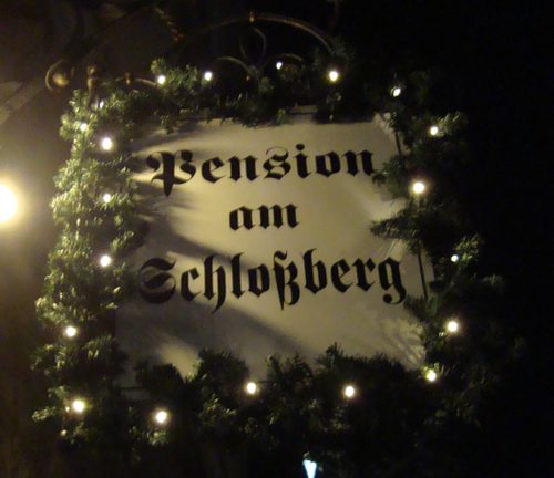 Beleuchtetes Pensionsschild bei Nacht, weihnachtlich dekoriert