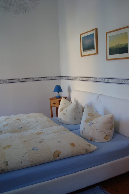 Gästezimmer mit gepolstertem Kopfteil und Landschaftsbildern