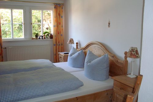 Doppelzimmer mit hellem Fenster und rustikalem Holzbett