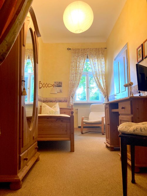 Einzelzimmer im Vintage-Stil mit antikem Kleiderschrank und Spiegel